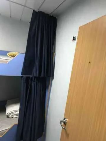 Curtained Bunk Bed Next to a Wooden Door in a Small Room — NT Blinds in Yarrawonga, NT