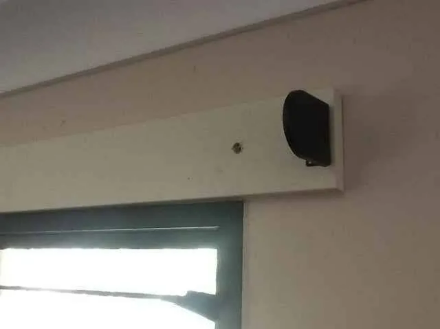 Wall-mounted Black Speaker Above a Window in a Beige Room — NT Blinds in Yarrawonga, NT