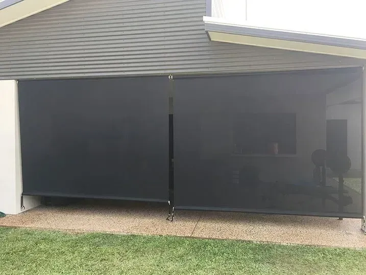 Side view of a dark gray building with a black awning extended, narrow walkway next to a fence  — NT Blinds in Yarrawonga, NT