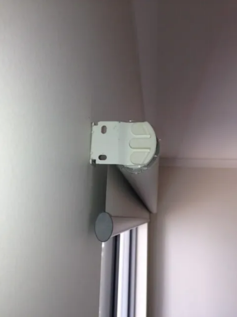 White Window Blind Roller Mounted Near a Ceiling Corner Above a Window — NT Blinds in Yarrawonga, NT