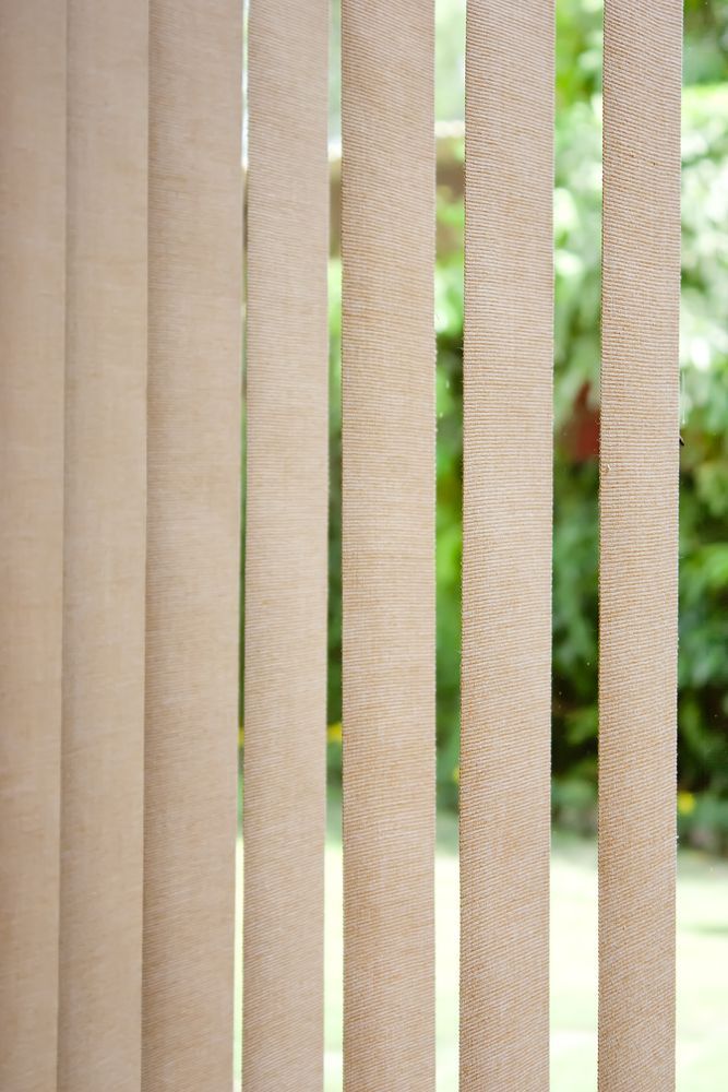 Beige Vertical Blinds Against a Blurred Green Outdoor Background — NT Blinds in Yarrawonga, NT