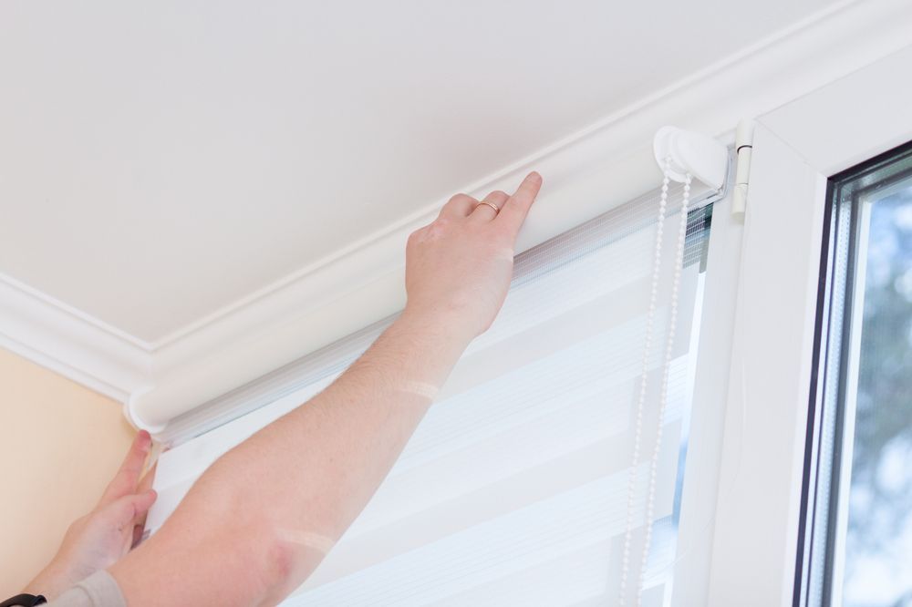 Hands Adjusting White Blinds Beside a Window Frame — NT Blinds in Yarrawonga, NT