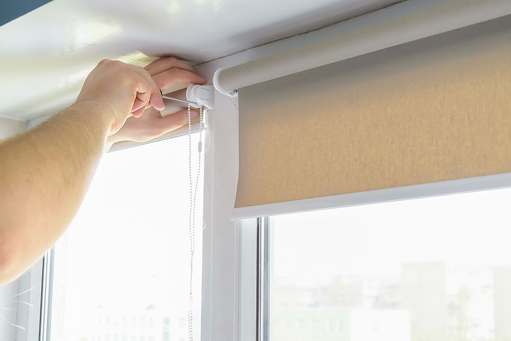 Person Installing a Beige Roller Blind in a White Window Frame — NT Blinds in Fannie Bay, NT