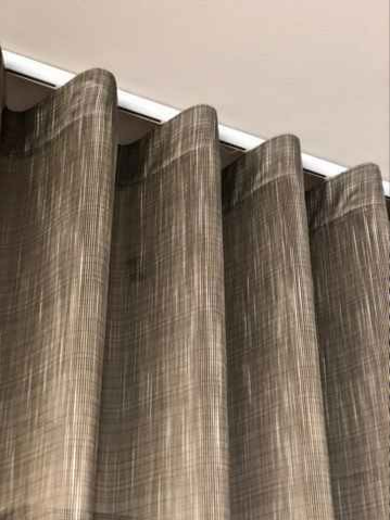 Gray Pleated Curtains Hanging From a Ceiling Track Near a White Wall — NT Blinds in Yarrawonga, NT