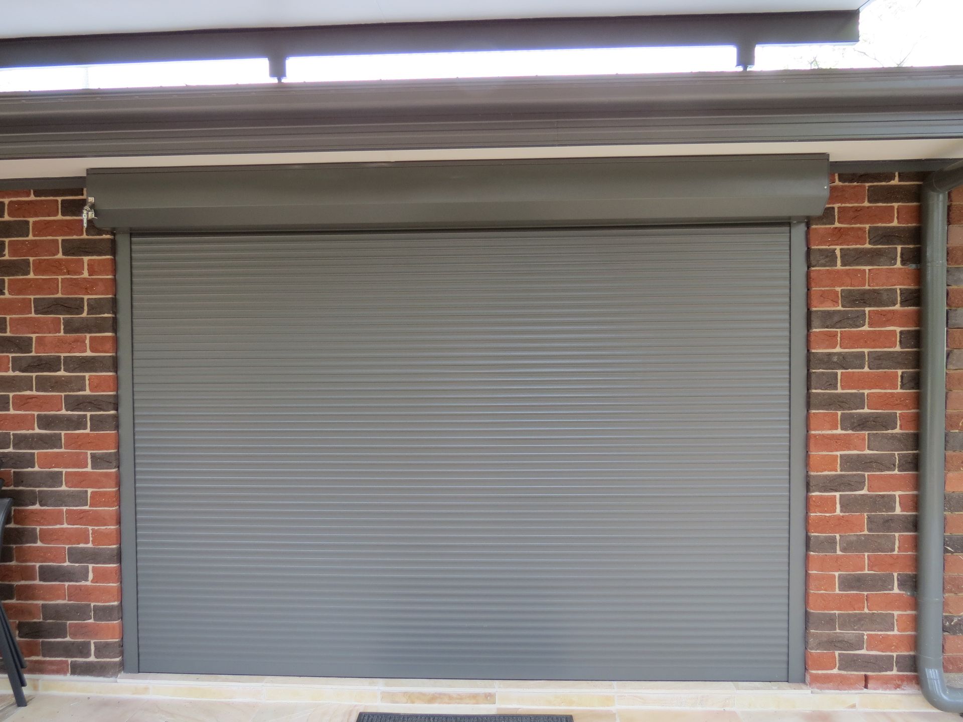 Gray roller shutter door on a red brick wall  — NT Blinds in Yarrawonga, NT