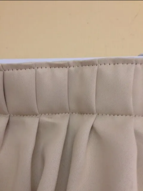 Close-up of a Beige Quilted Curtain With a White Trim Against a Tan Wall — NT Blinds in Yarrawonga, NT