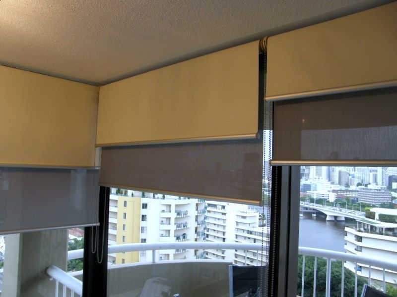 Neutral-toned window blinds partially cover a window with a city view  — NT Blinds in Yarrawonga, NT