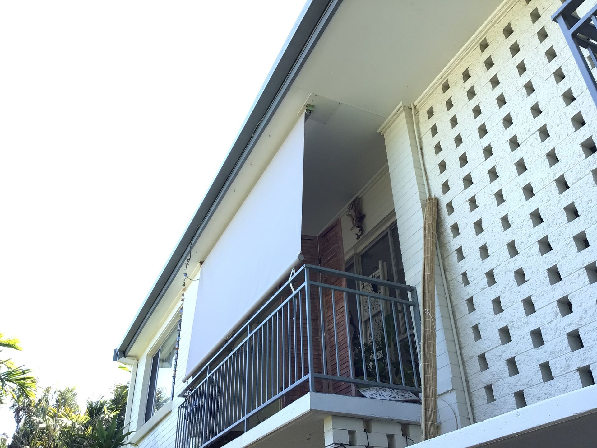 Exterior view of a building with a balcony, white walls, and a retractable sunshade  — NT Blinds in Humpty Doo, NT