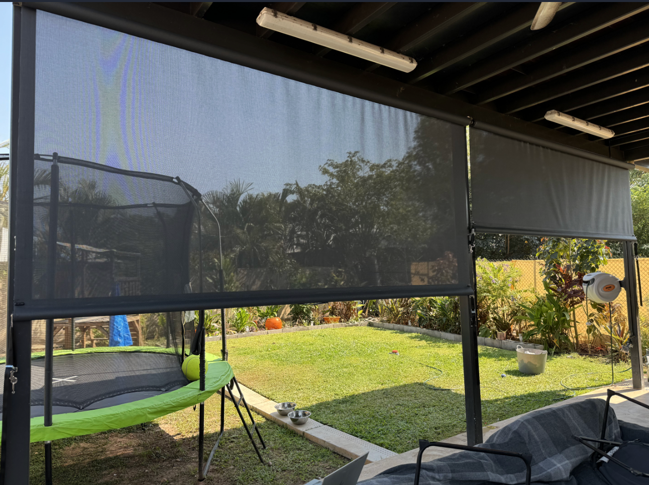 Outdoor patio with two black sunshades, trampoline, and backyard view  — NT Blinds in Humpty Doo, NT