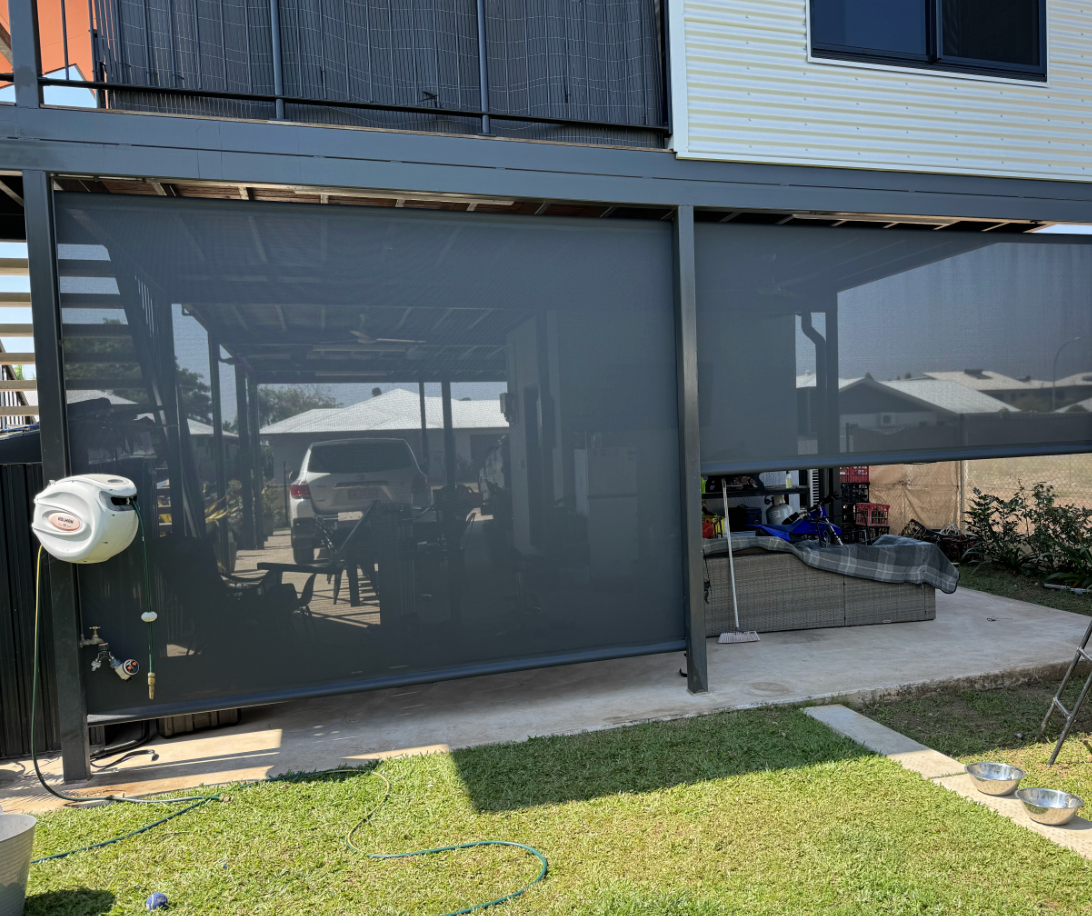 Dark grey outdoor blinds covering a patio area, with a car visible through the mesh.
