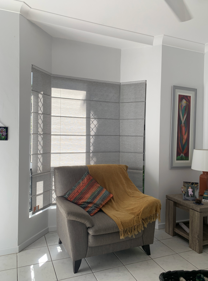 Cozy corner with a gray chair, Roman shades, and a yellow throw blanket, creating a comfortable indoor setting — NT Blinds in Yarrawonga, NT
