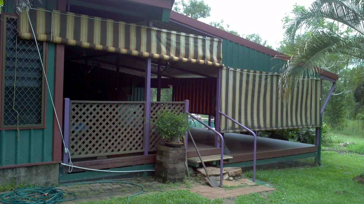 Small Green House With Striped Awnings, Porch Railing — NT Blinds in Yarrawonga, NT