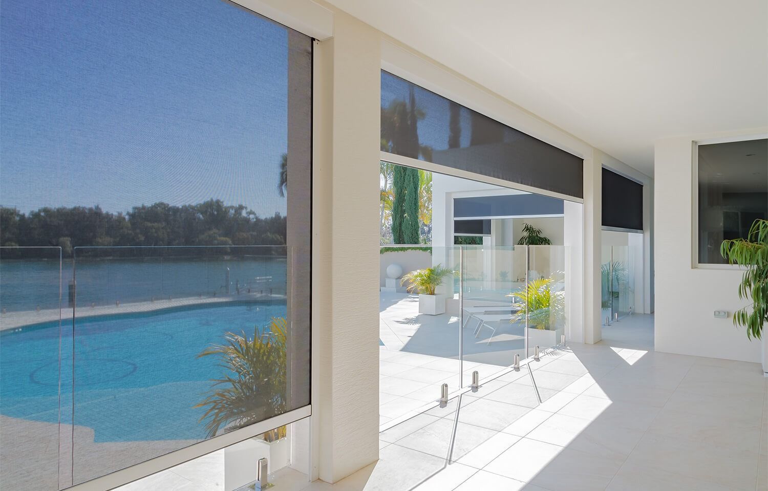 Modern patio with sliding glass doors opening to a bright poolside terrace and blue swimming pool — NT Blinds in Yarrawonga, NT