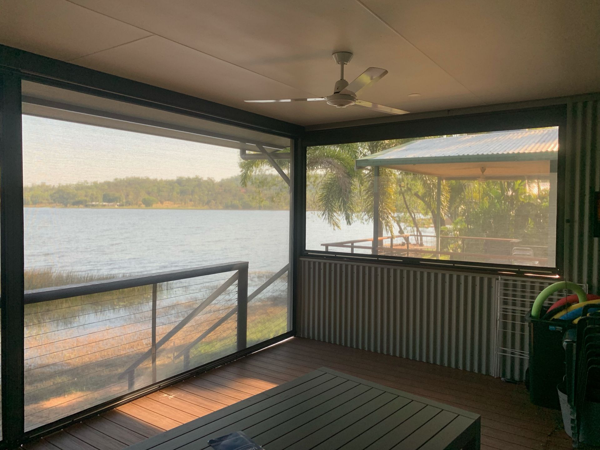 Roller shades with tree shadows cast on them. Green trees are visible through the shades — NT Blinds in Yarrawonga, NT