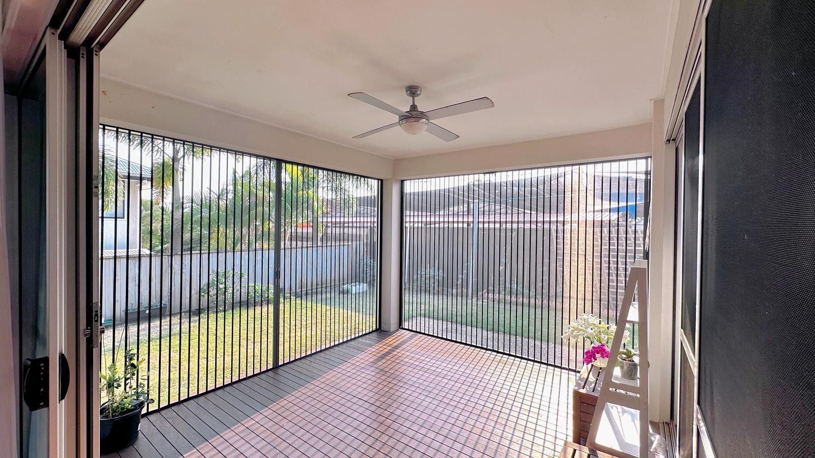 Covered porch with metal slat screens overlooking a yard with greenery and a walkway  — NT Blinds in Yarrawonga, NT