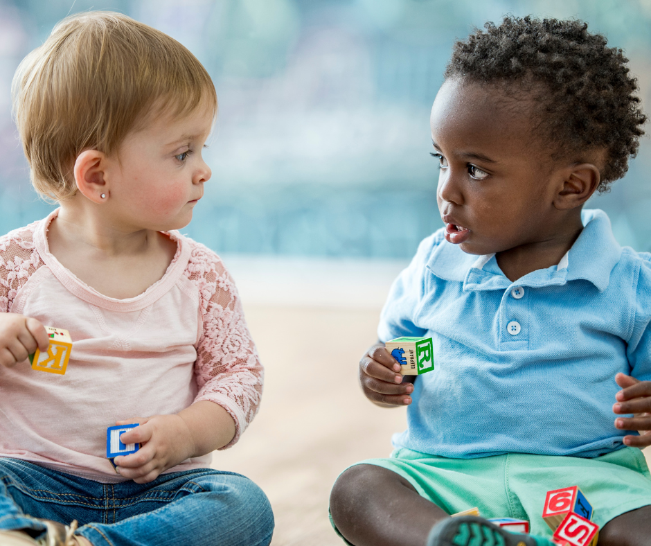 A boy and a girl are sitting next to each other playing with blocks.