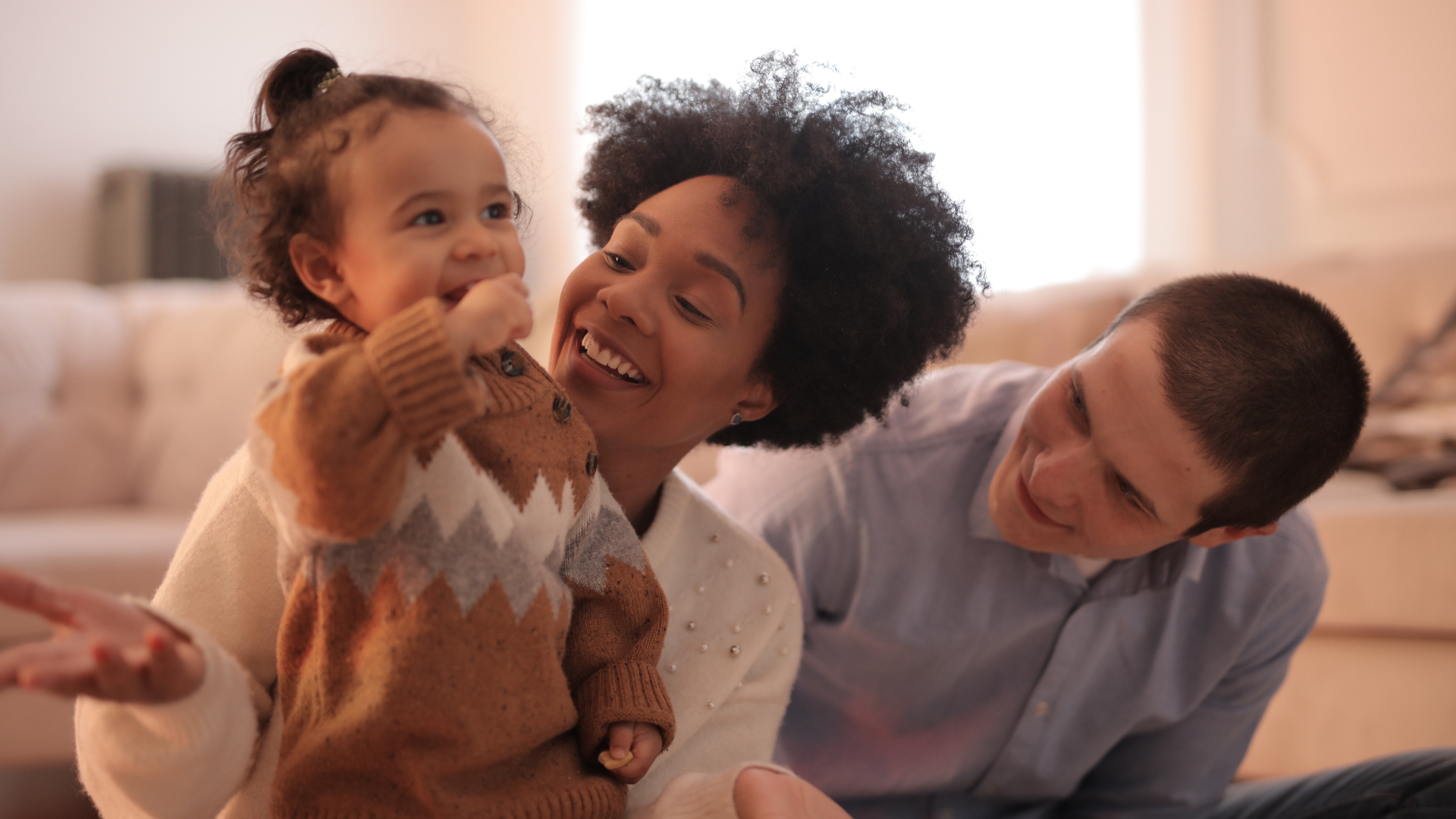 A family is sitting on the floor in a living room.