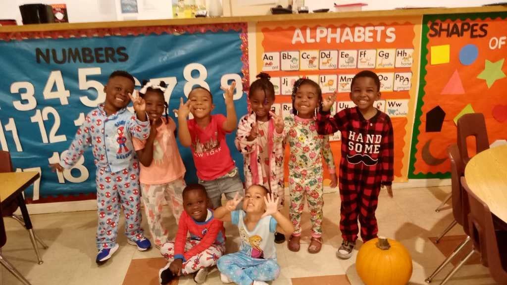 A group of children in pajamas are posing for a picture in a classroom.