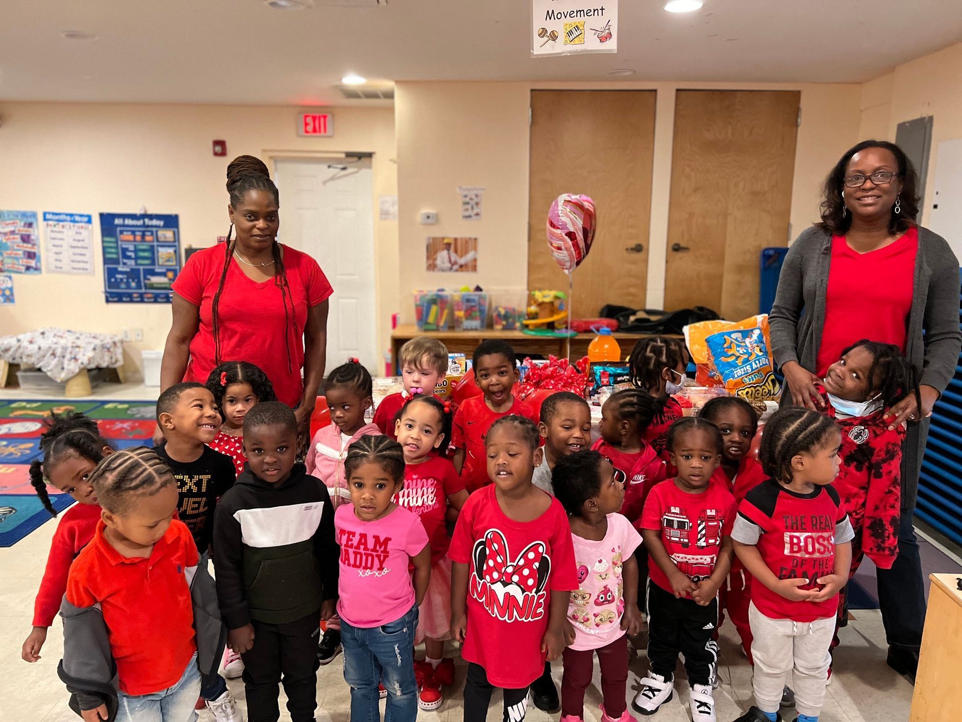 A group of children wearing red shirts are standing next to each other in a room.