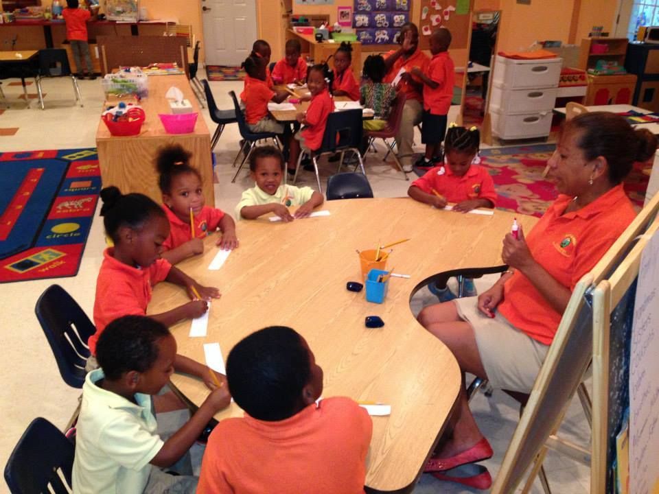 A group of children are sitting around a table in a classroom