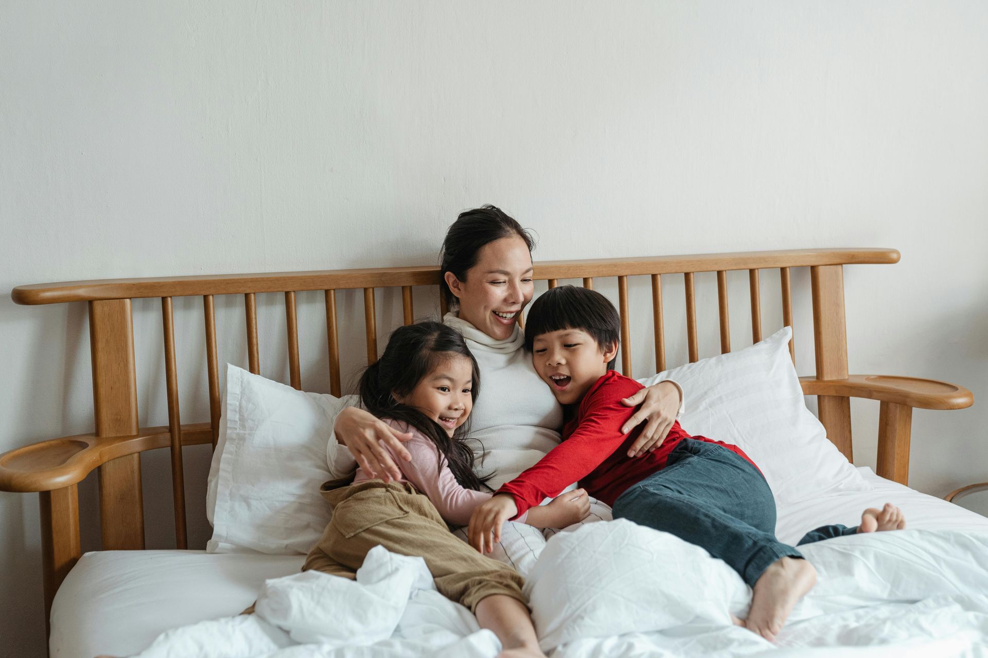 A woman and two children are sitting on a bed.