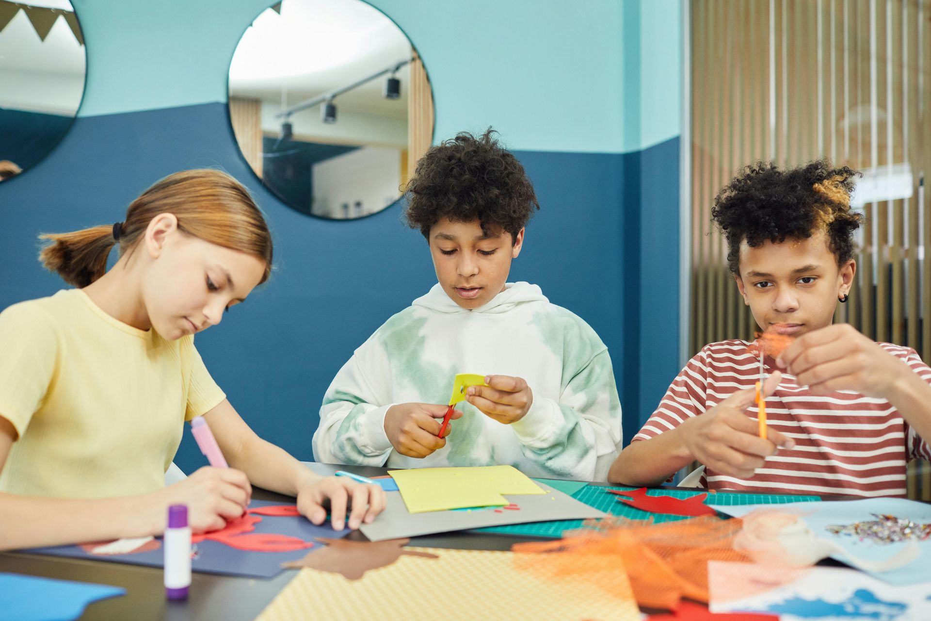 A group of children are sitting at a table making crafts.