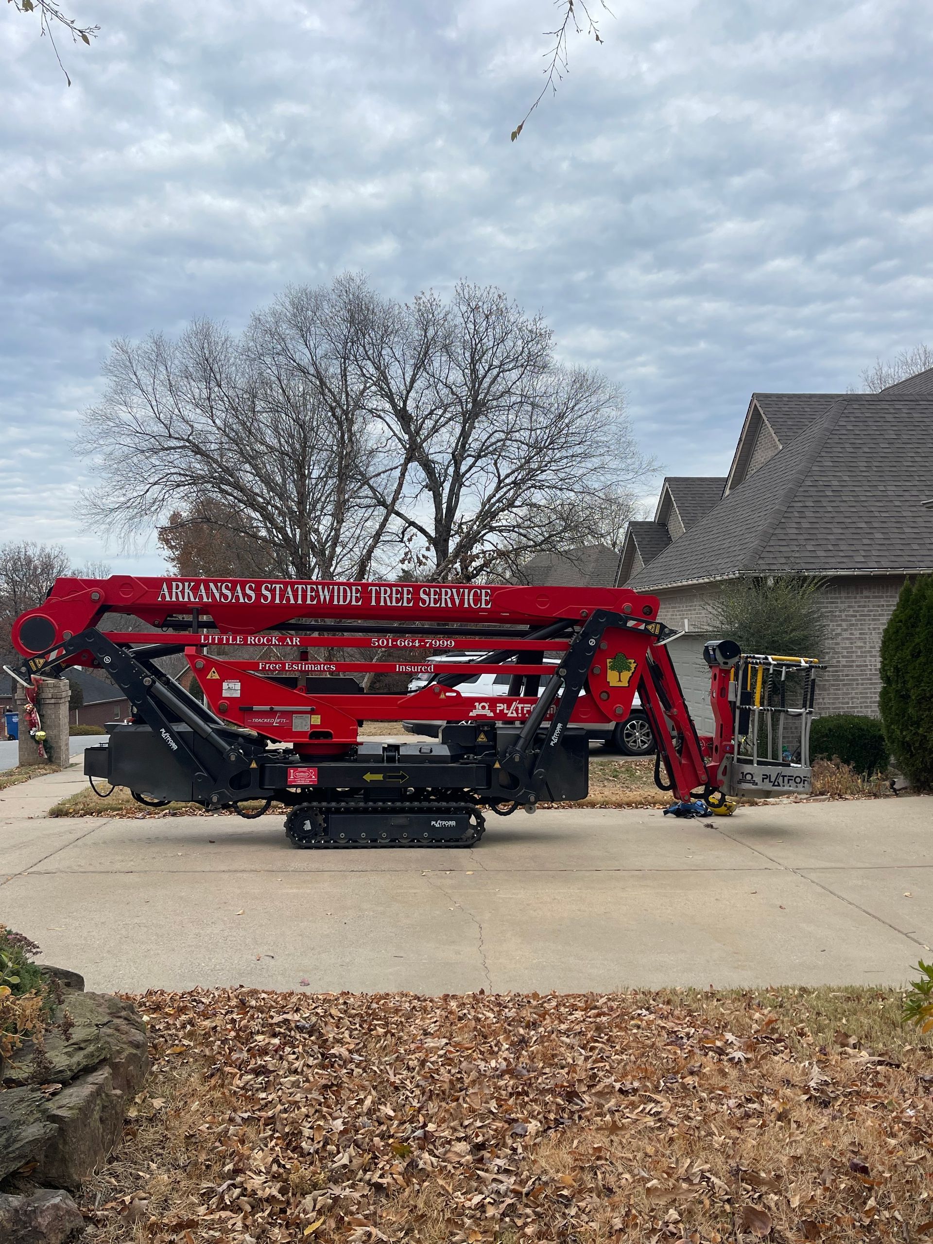 a red crane is parked in a driveway in front of a house .
