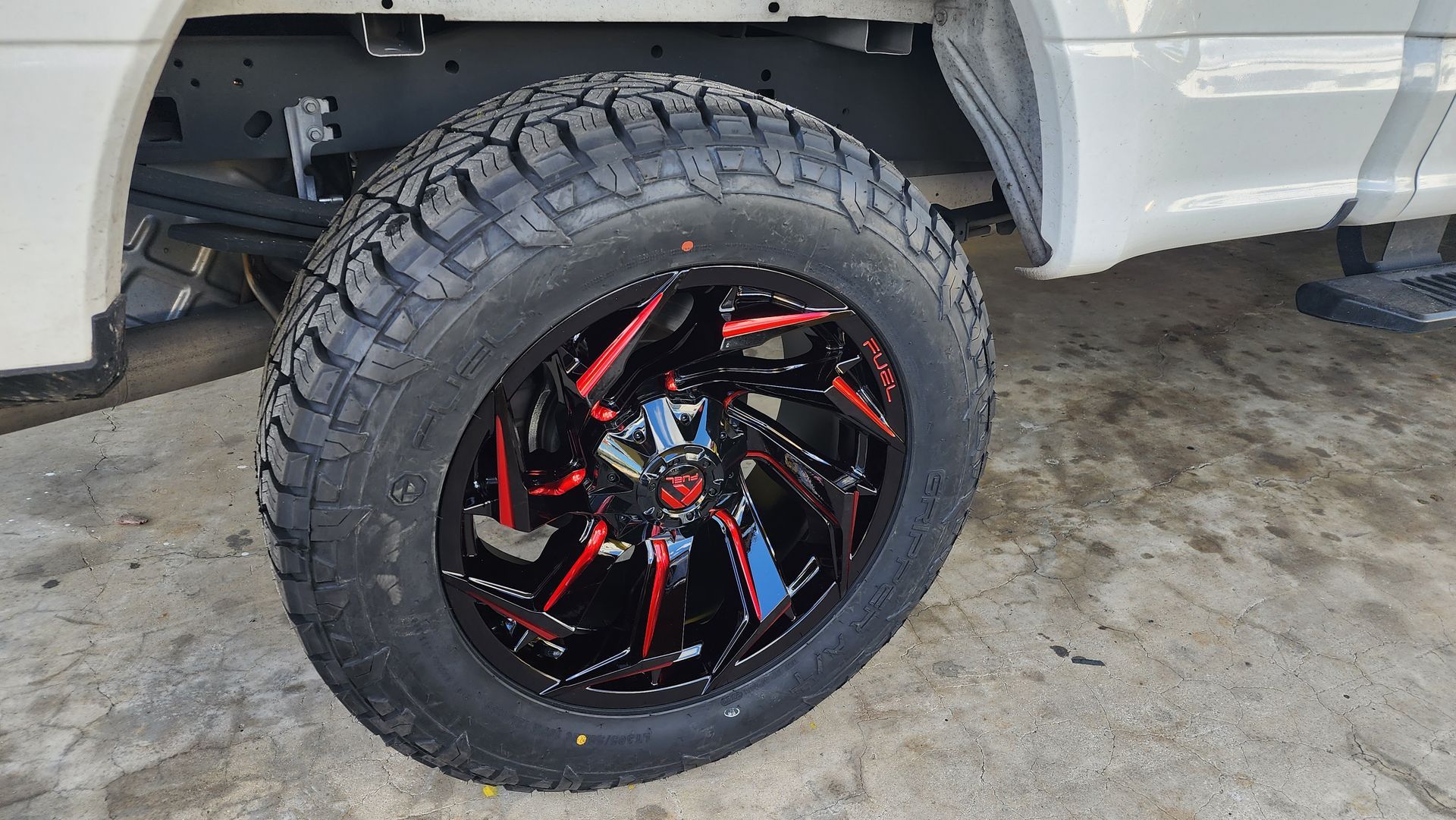 Black truck tire with red accents on a black rim.