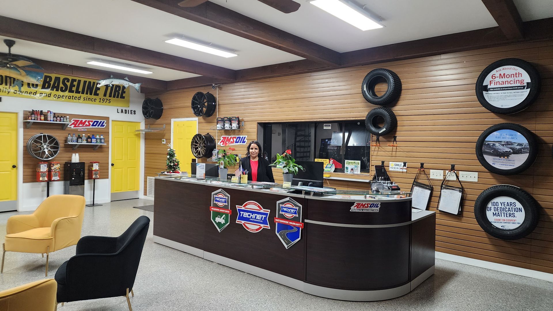 Interior of Baseline Tire shop. A person stands at a reception desk. Tires and promotional items decorate the walls.