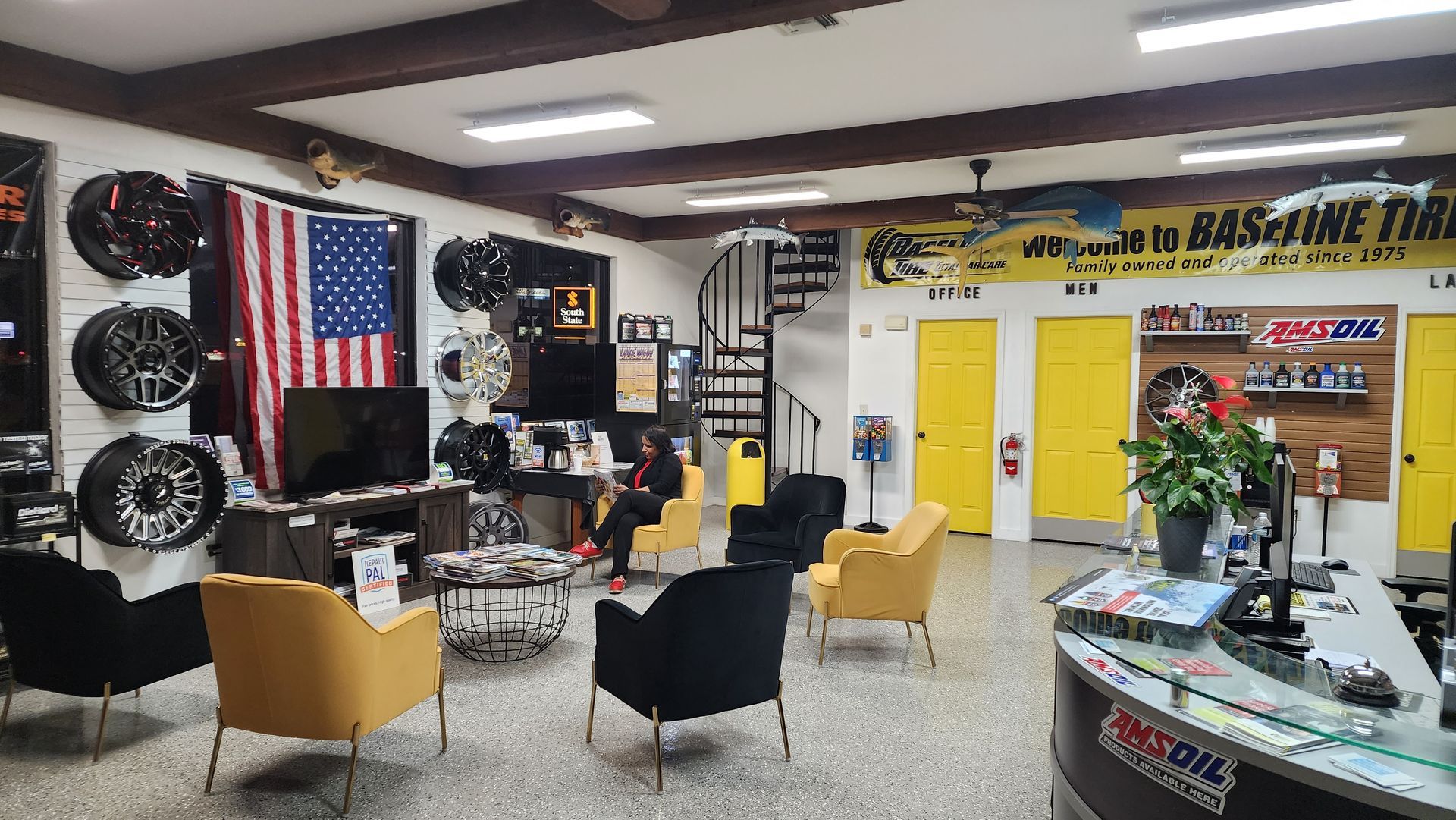 Interior of a tire shop with seating area, wheels on display, and an American flag.