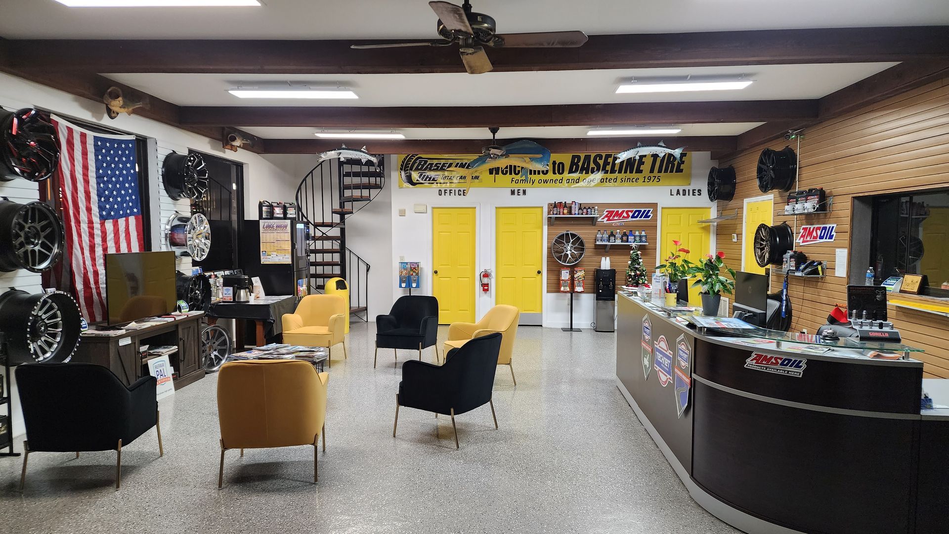 Interior of a tire shop with wheels on display, chairs, and an American flag.