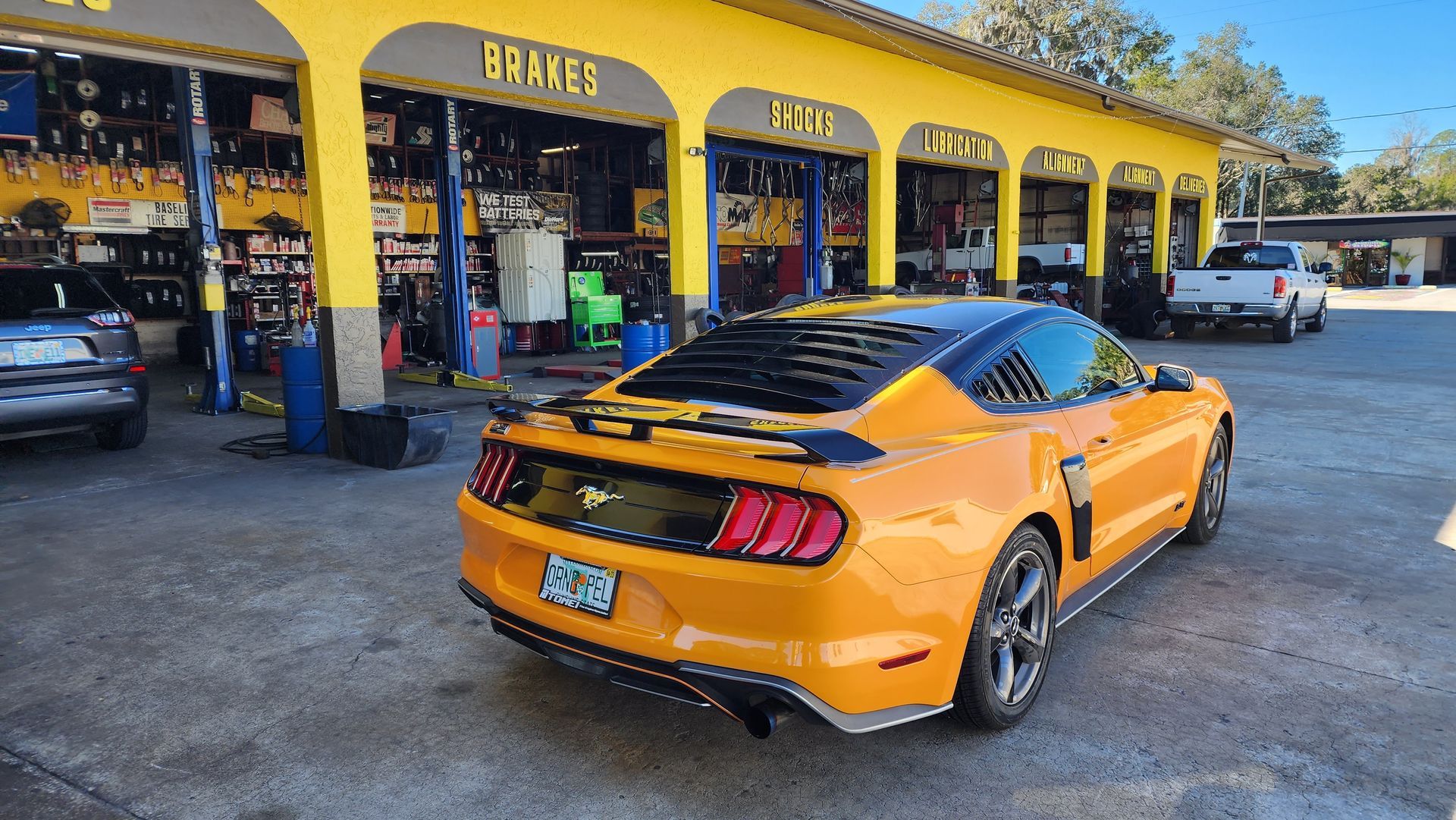 Yellow Ford Mustang parked outside a yellow auto repair shop.