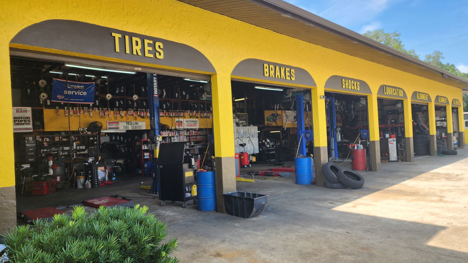 Yellow auto repair shop with open bays, signage, and equipment.