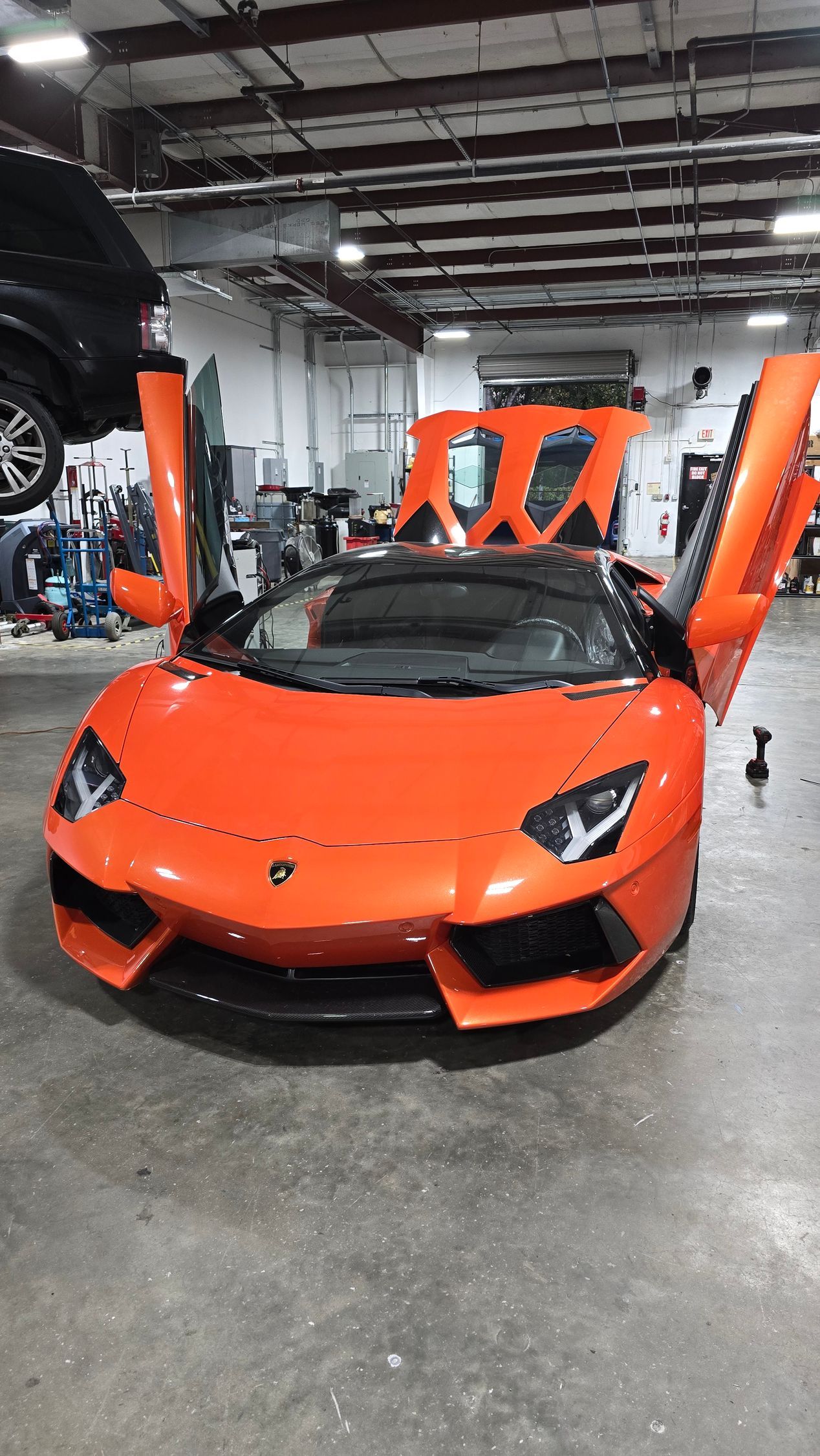 Orange Lamborghini with open doors inside a garage.