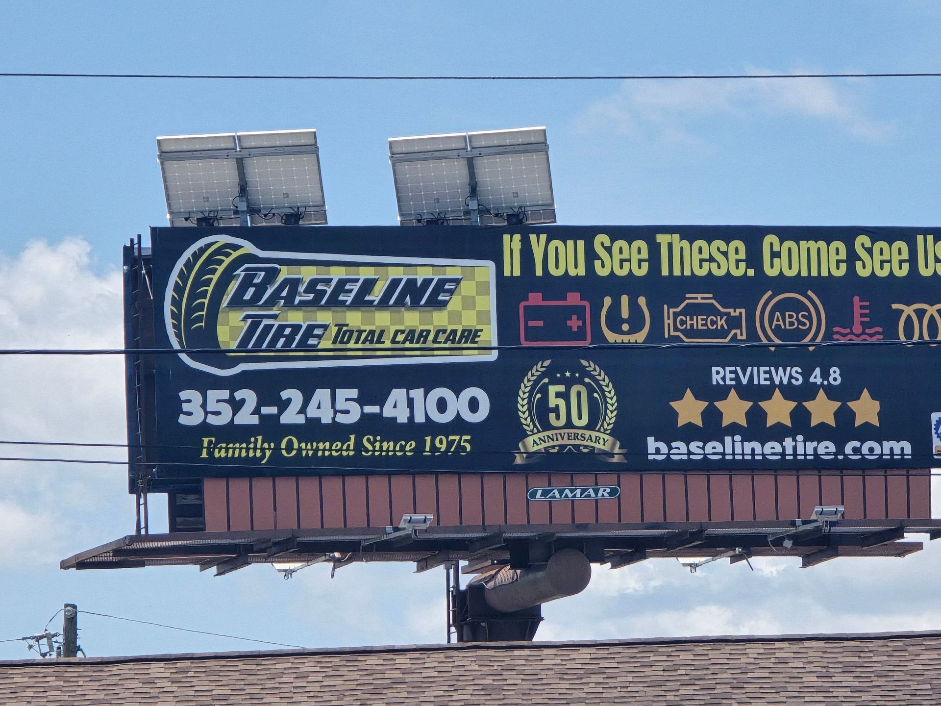 Billboard for Baseline Tire with text and contact info, topped with solar panels.
