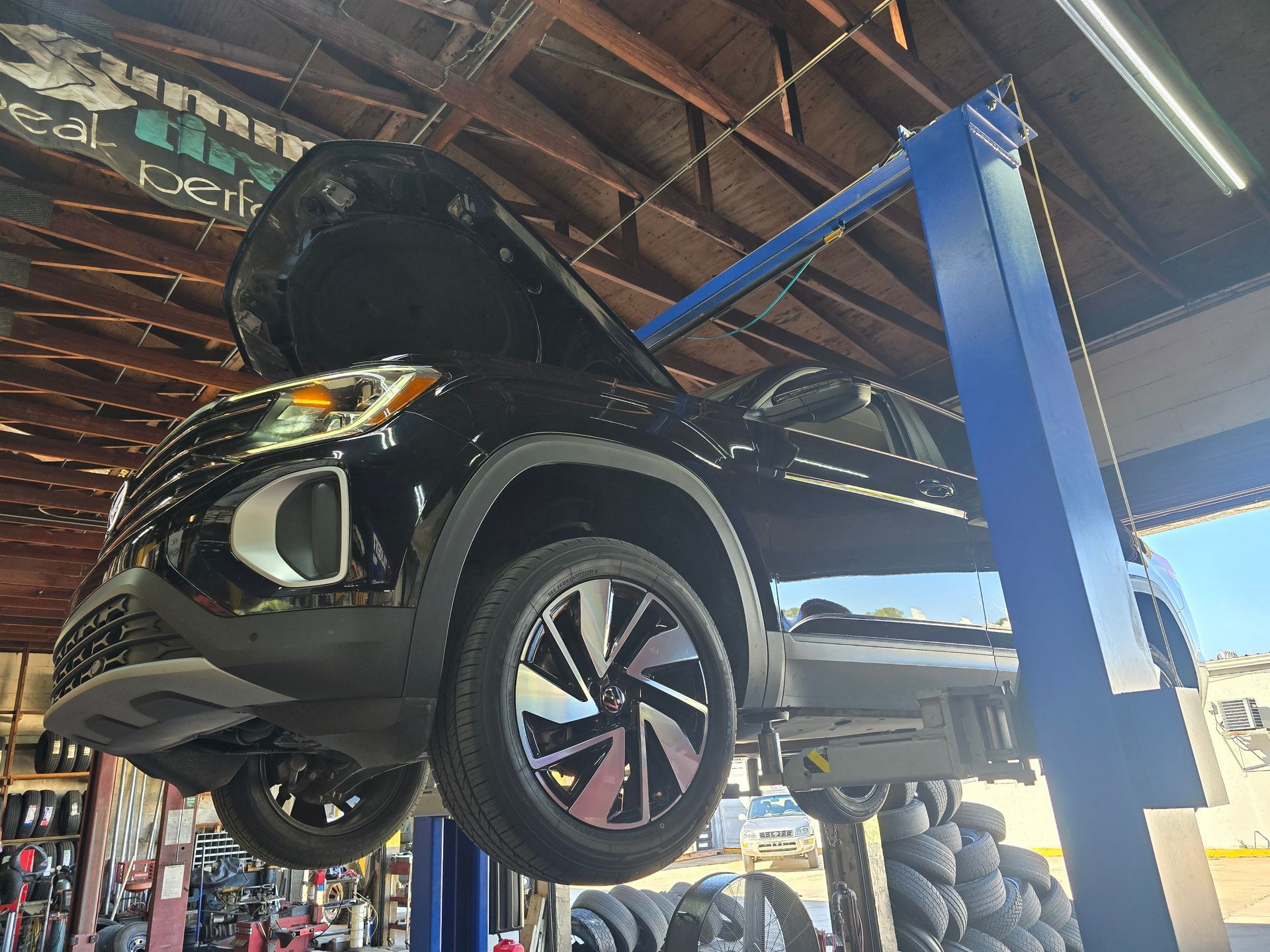 Black SUV on a blue car lift inside a shop with the hood open.