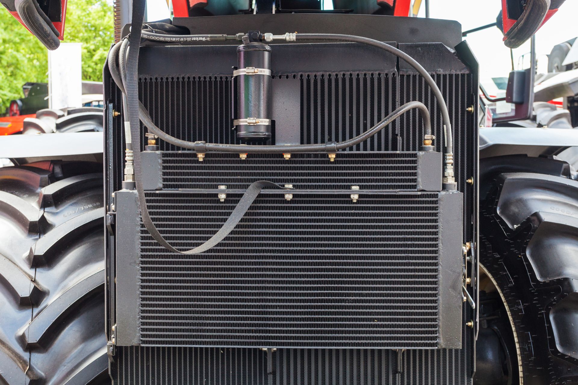 Front of a tractor, showing a radiator with hoses and a filter.