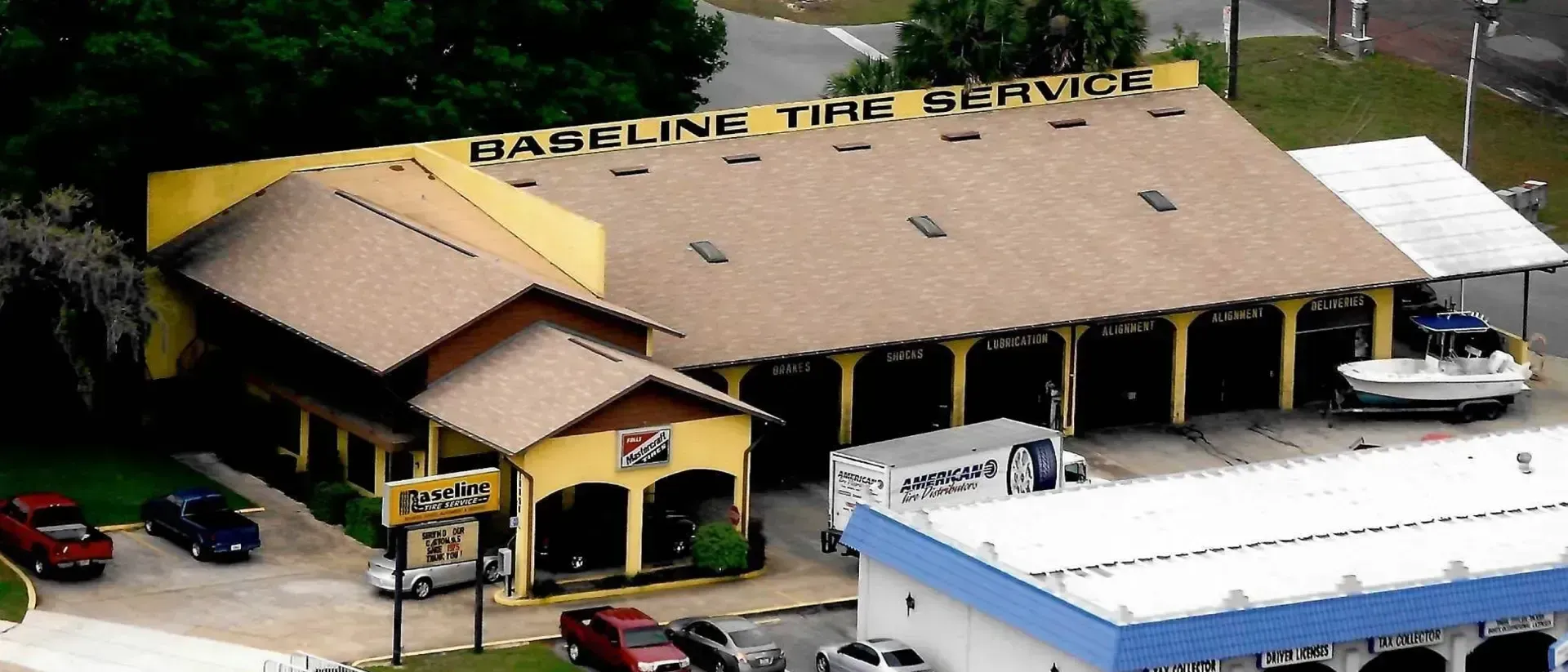 Baseline Tire Service building with cars parked out front, a boat on a trailer, and a truck.