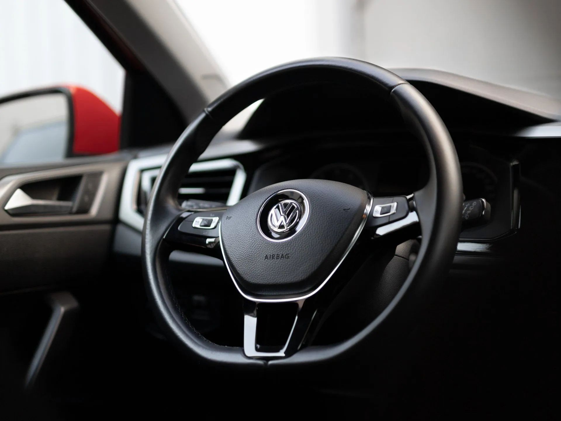 Black steering wheel with VW logo in car interior.