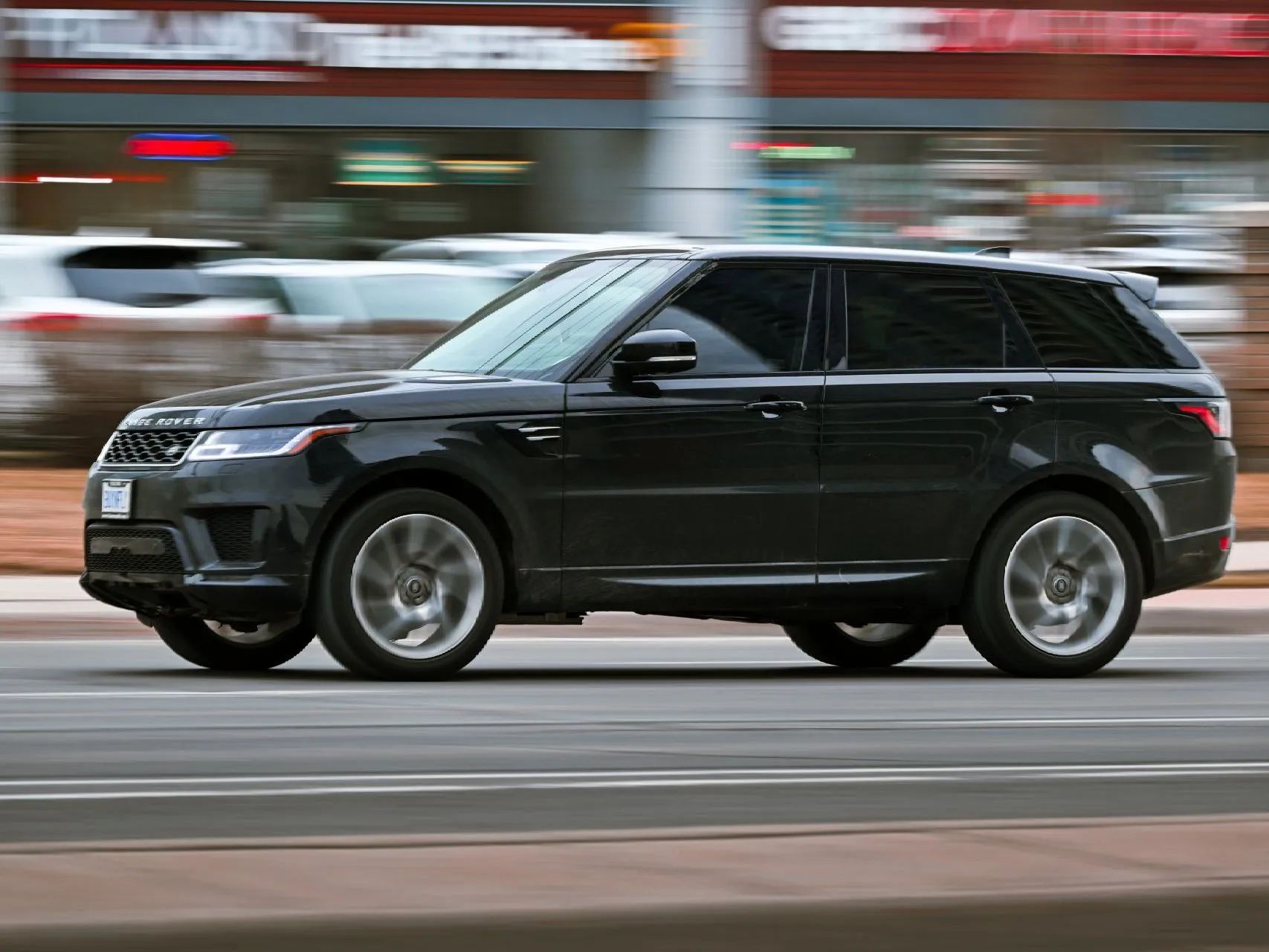 Black Range Rover Sport SUV driving on a street, blurred background.