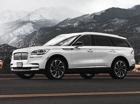 White Lincoln Aviator SUV on a road with snowy mountains in the background.
