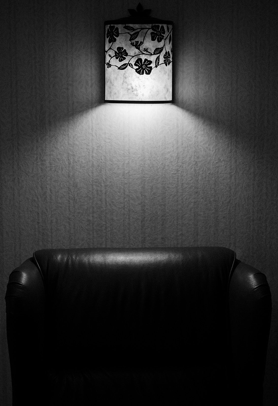 A dark chair waits in silence under the beautiful light at Rim Rock Resort Hotel.