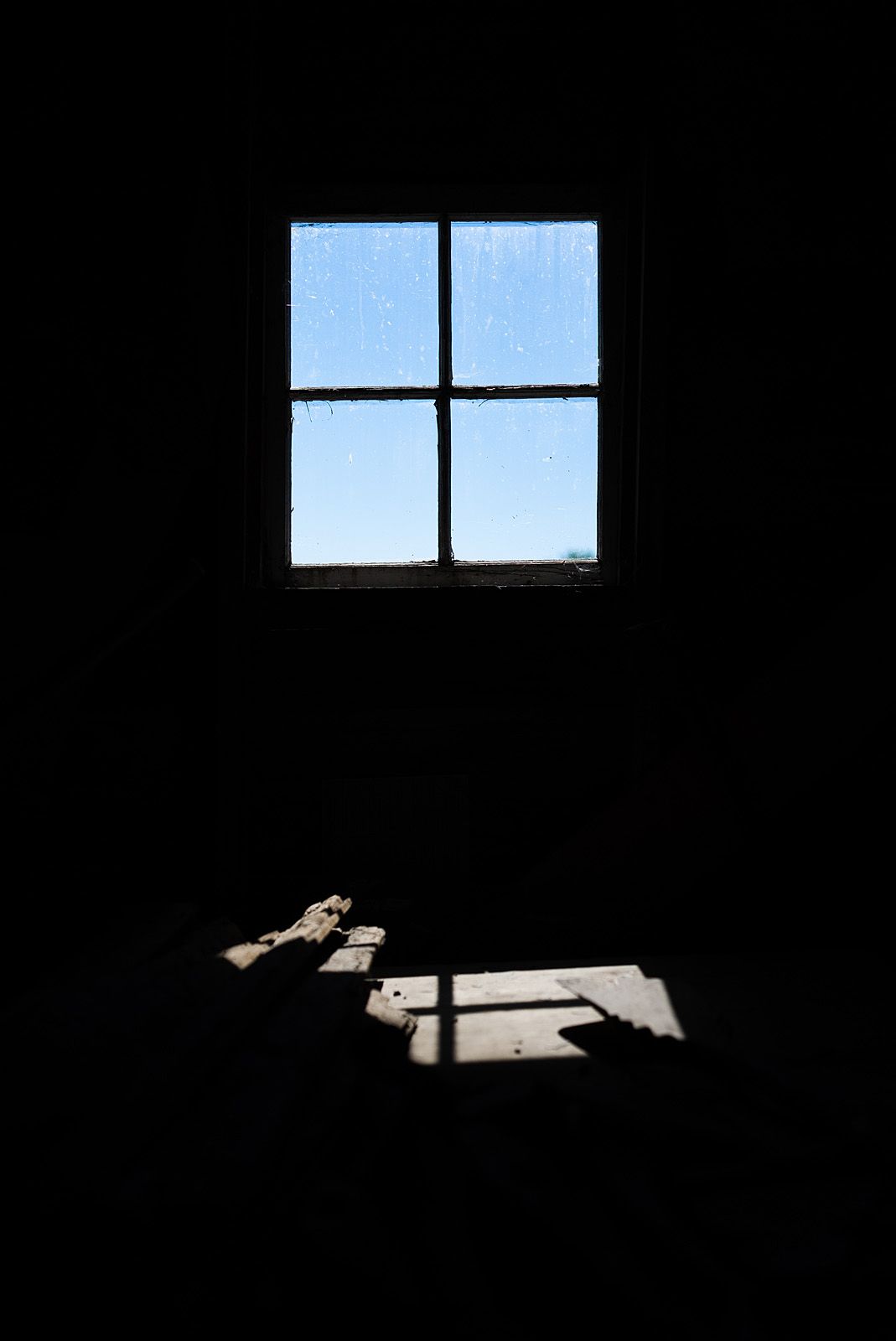 In the darkened blacksmith shop, only a window casts light.