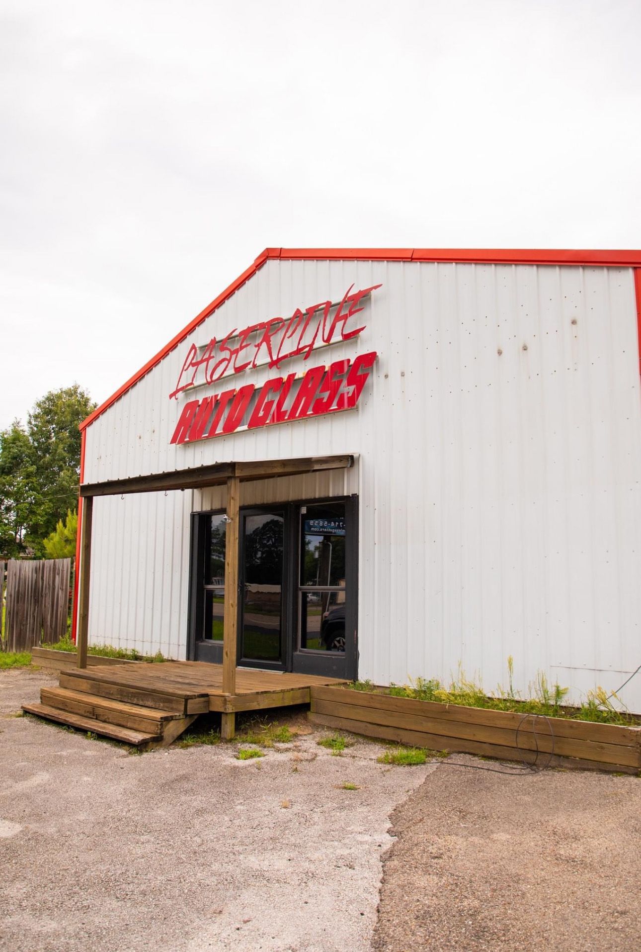 A white building with a red roof and a red sign on the side of it.