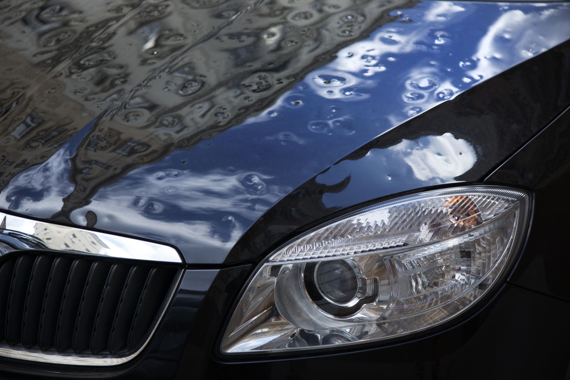 A close up of a car hood with water drops on it