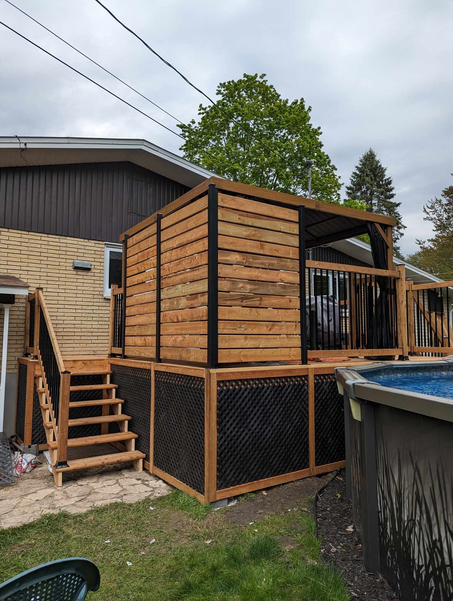 Une terrasse en bois avec des escaliers et une piscine dans l'arrière-cour d'une maison.