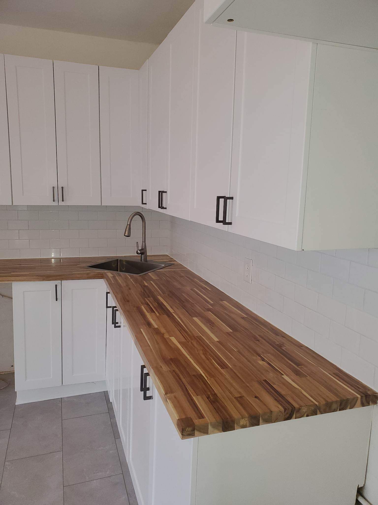 Une cuisine avec des armoires blanches et un comptoir en bois