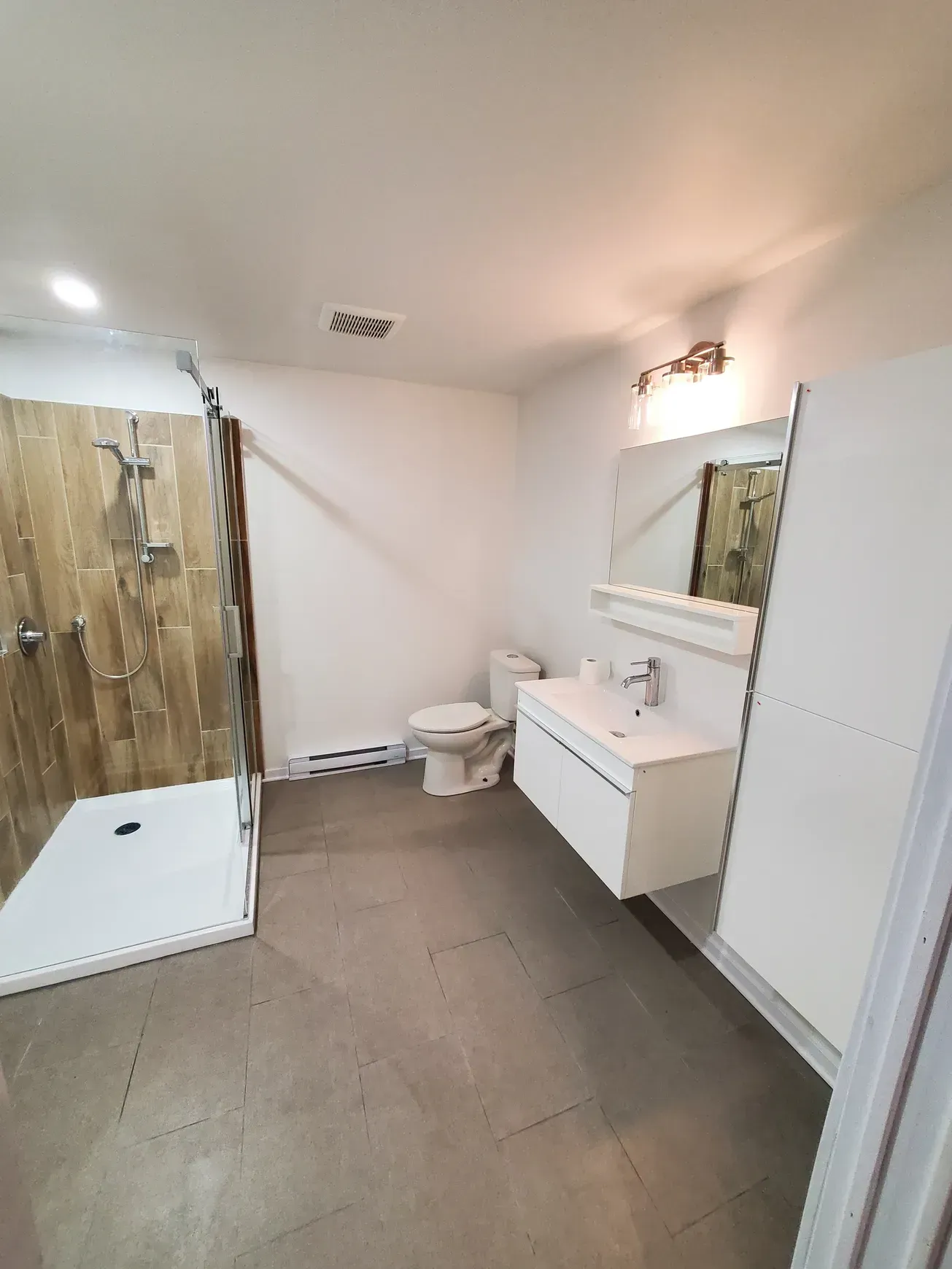 Salle de bains moderne avec murs blancs, meubles en bois et miroir rond.