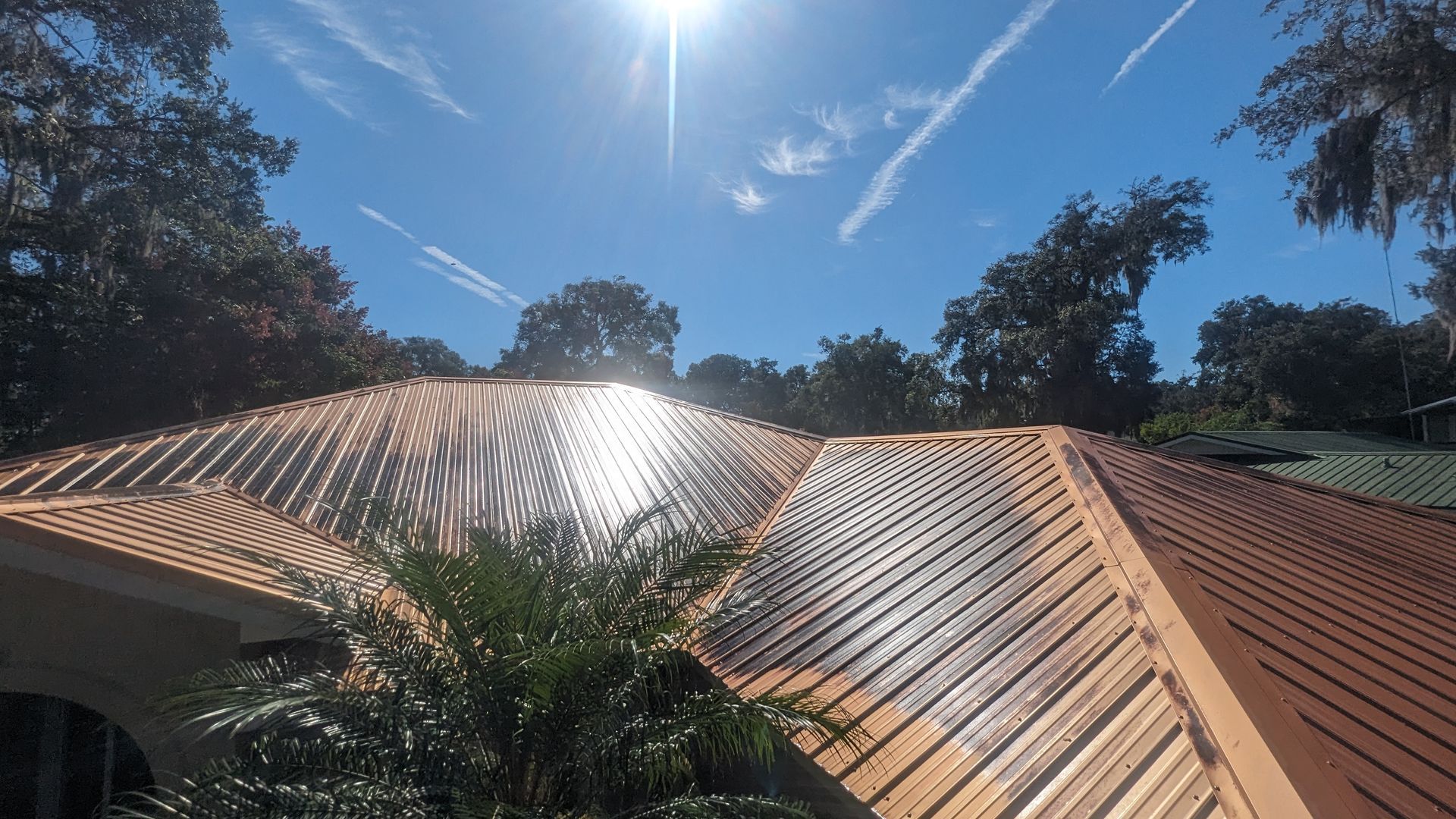 A roof in the middle of a reroofing project, showing bare wooden decking alongside installed reddish-brown tiles.