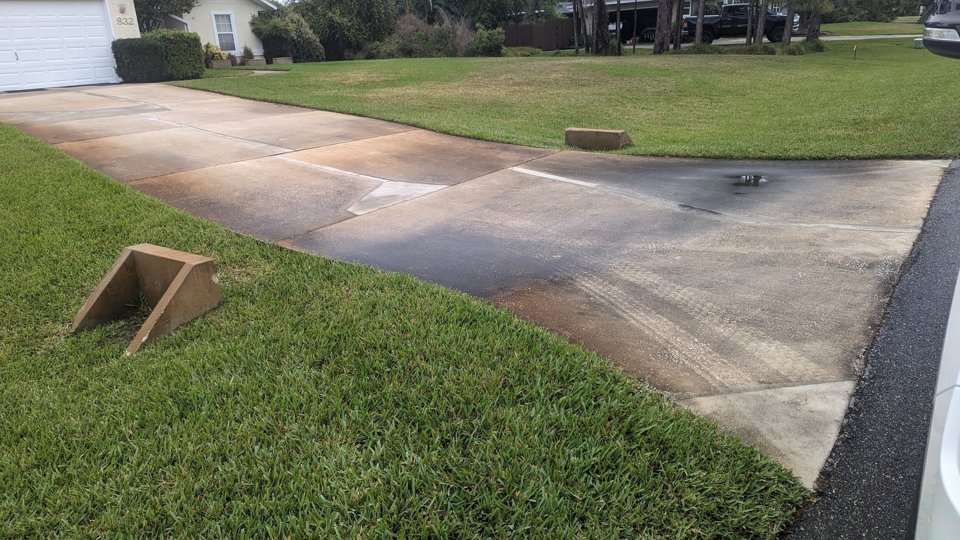 A concrete driveway with a ramp curb in the foreground and a house in the background.